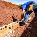 Trabalhador da construção civil atua na preparação da fundação de uma obra ao ar livre.