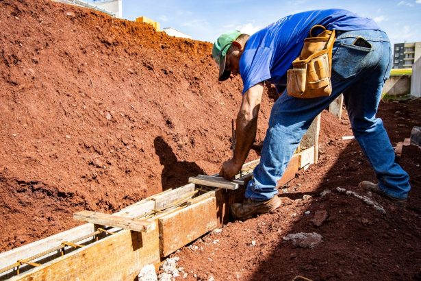 Trabalhador da construção civil atua na preparação da fundação de uma obra ao ar livre.