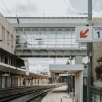 Plataforma de uma estação ferroviária urbana contemporânea em Lisboa, com linhas e estruturas de transporte.