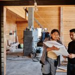 Trabalhadores da construção analisam plantas em um local de reforma.