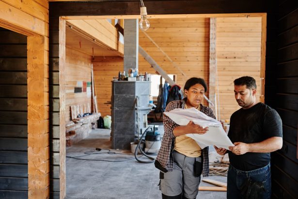 Trabalhadores da construção analisam plantas em um local de reforma.