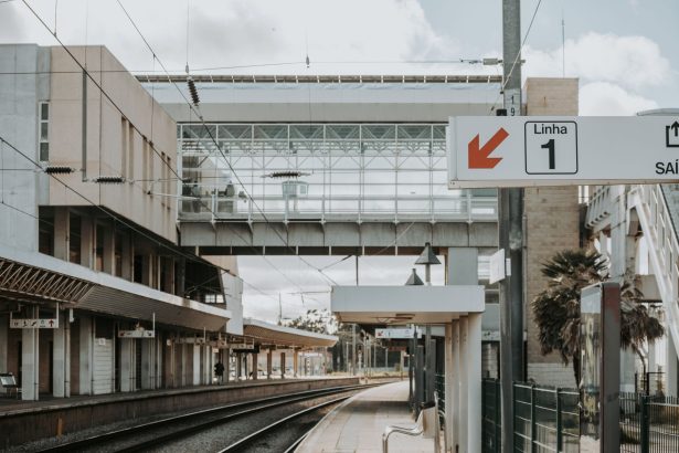 Plataforma de uma estação ferroviária urbana contemporânea em Lisboa, com linhas e estruturas de transporte.